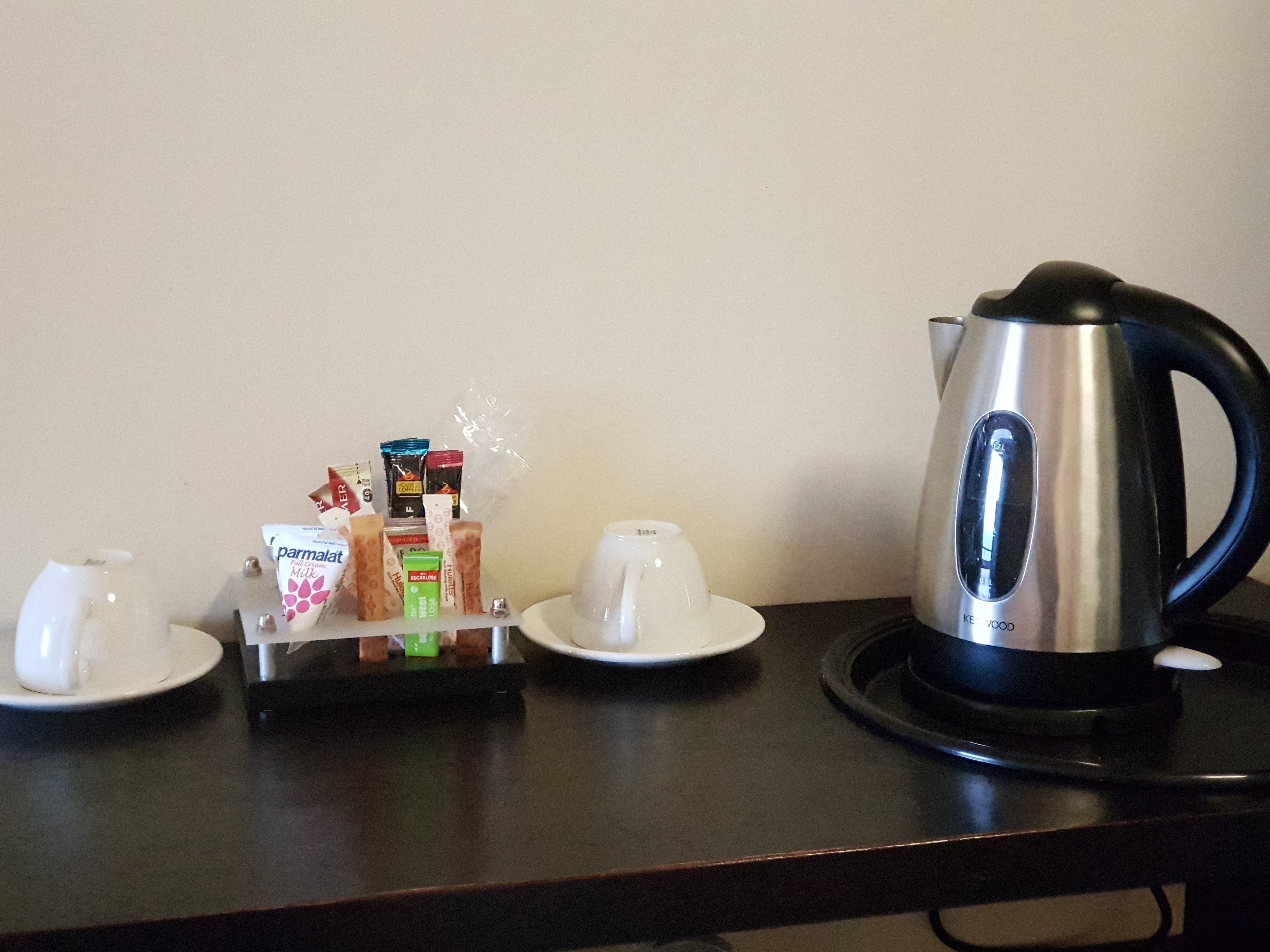 Un coin café équipé d’une bouilloire, de tasses et d’un plateau de dosettes de café.