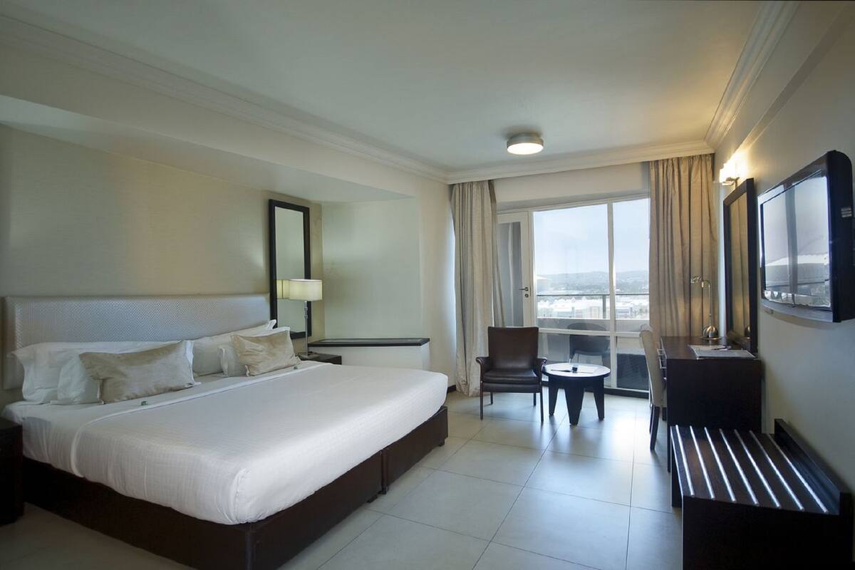 A hotel room with a large bed, a desk, a chair, and a TV.