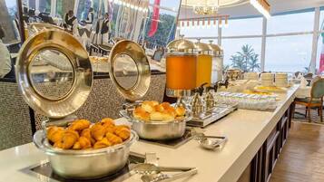 Ein reichhaltiges Buffet mit verschiedenen Speisen und Getränken, darunter Croissants und einem großen Getränkespender.