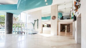 A spacious lobby with a high ceiling, a reception desk, and a glass elevator. - The Blue Waters Hotel (Durban)