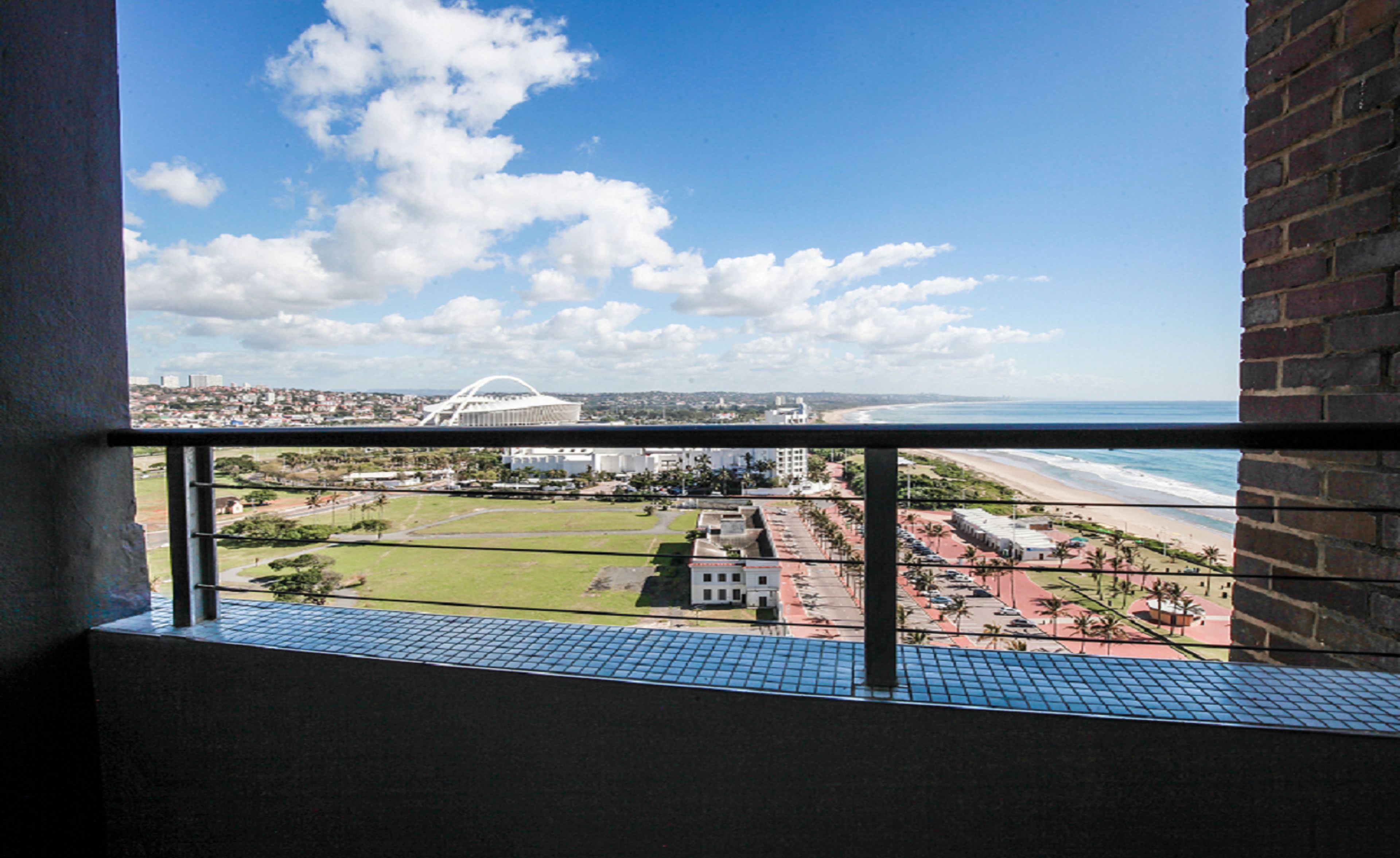 A balcony with a view of a beach, a stadium, and a cityscape.