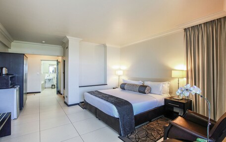 A hotel room with a bed, bedside tables, a desk, and a lamp.
