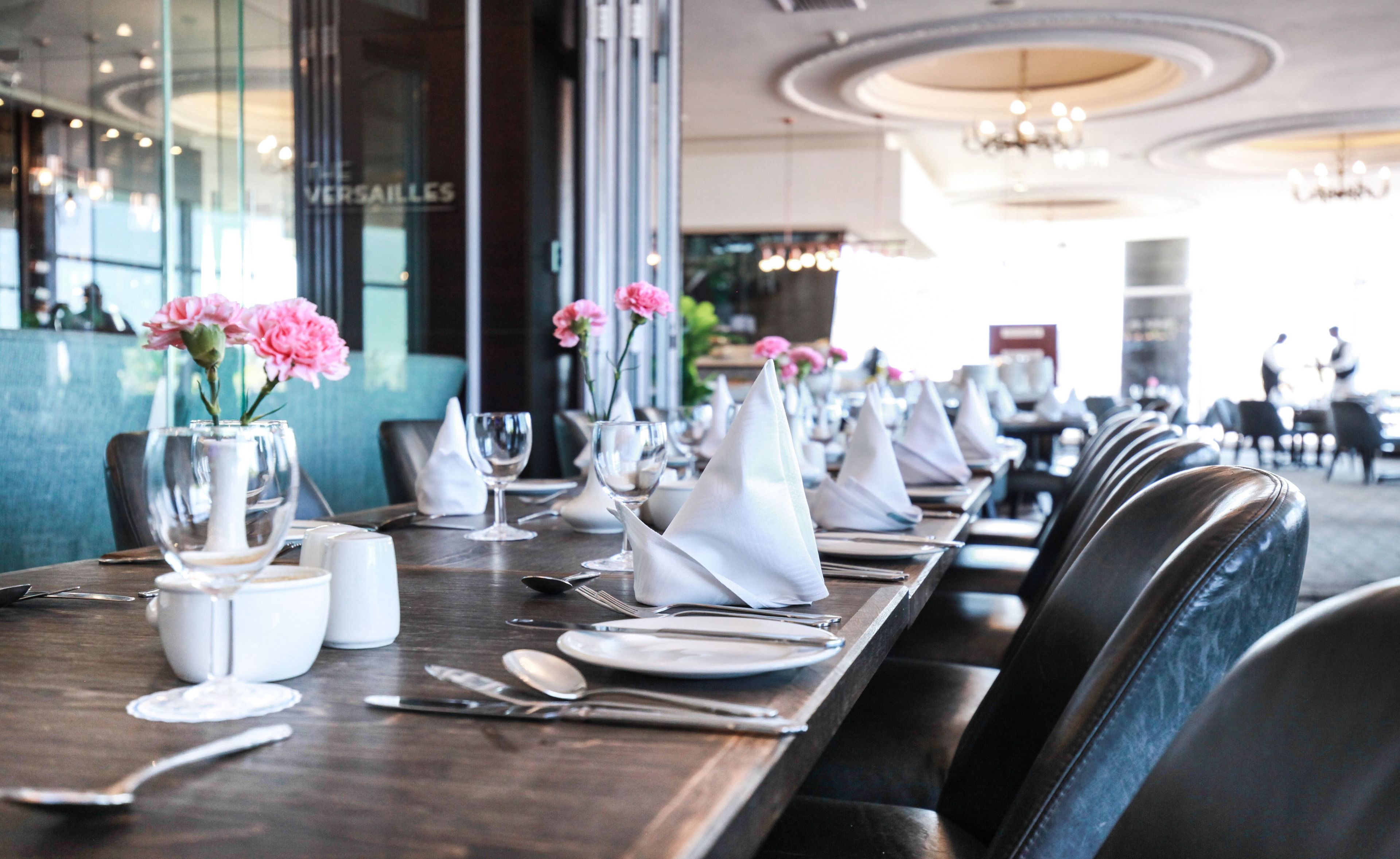 A restaurant setting with tables set for dining, including plates, cutlery, and napkins.