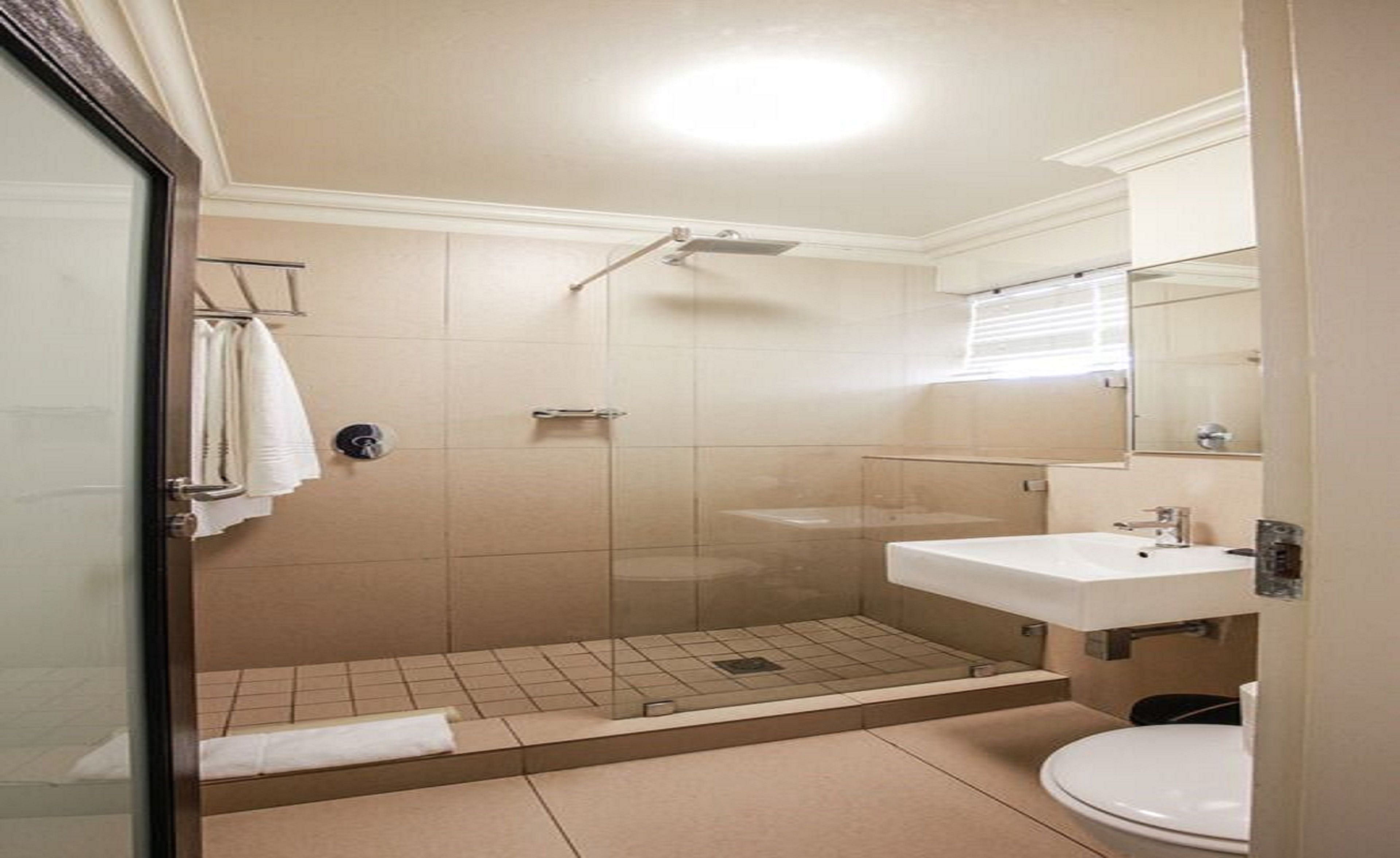 A bathroom with a glass-enclosed shower, a sink, and a toilet.