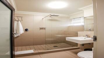 A bathroom with a glass-enclosed shower, a sink, and a toilet.