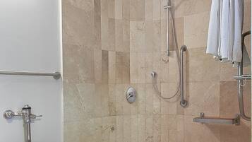 A bathroom with a toilet, a shower with a grab bar, and a towel rack.
