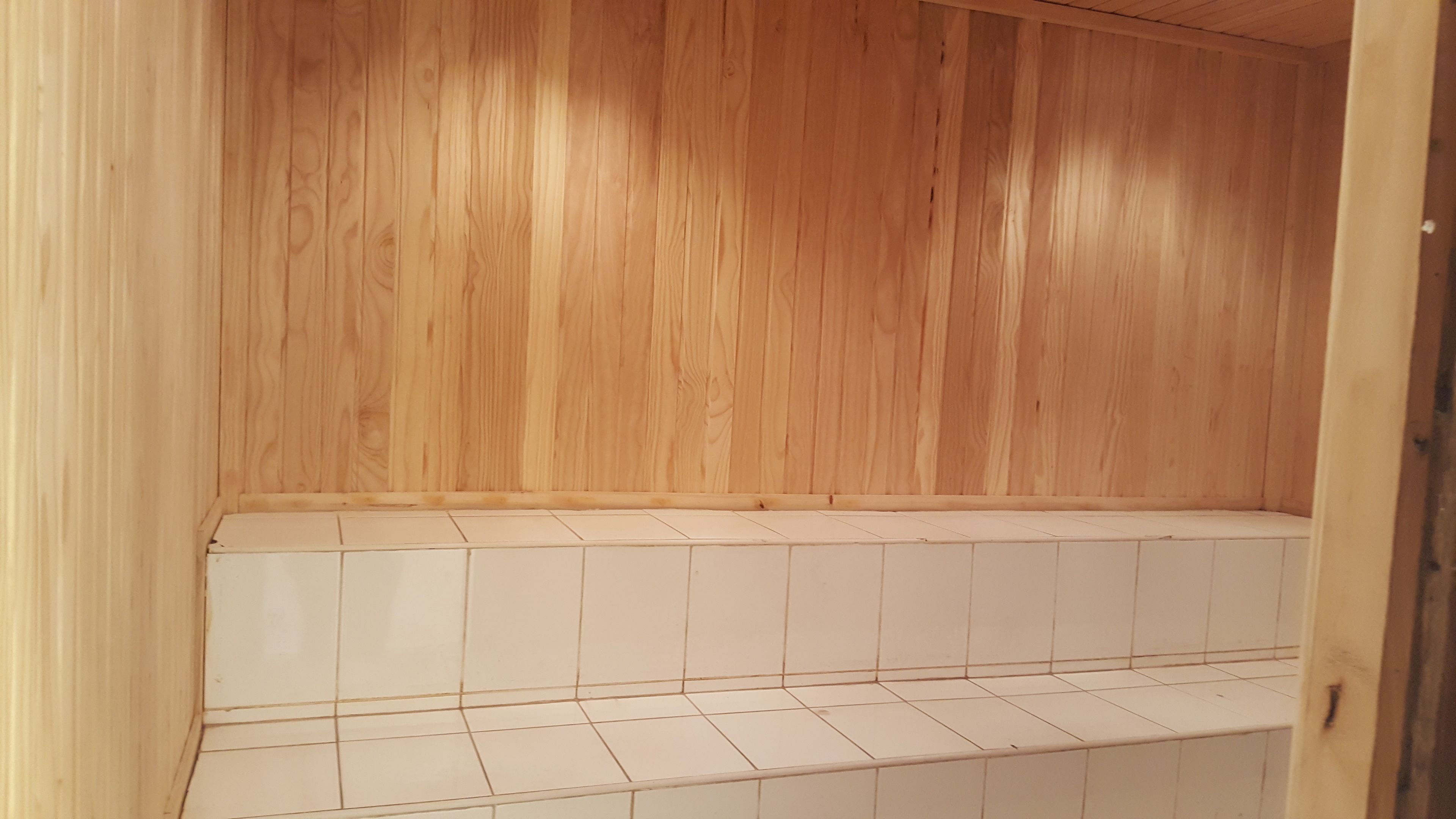 Una habitación de madera con suelo de baldosas y un banco de madera.