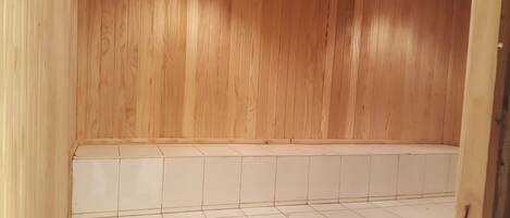 A wooden room with a tiled floor and a wooden bench.