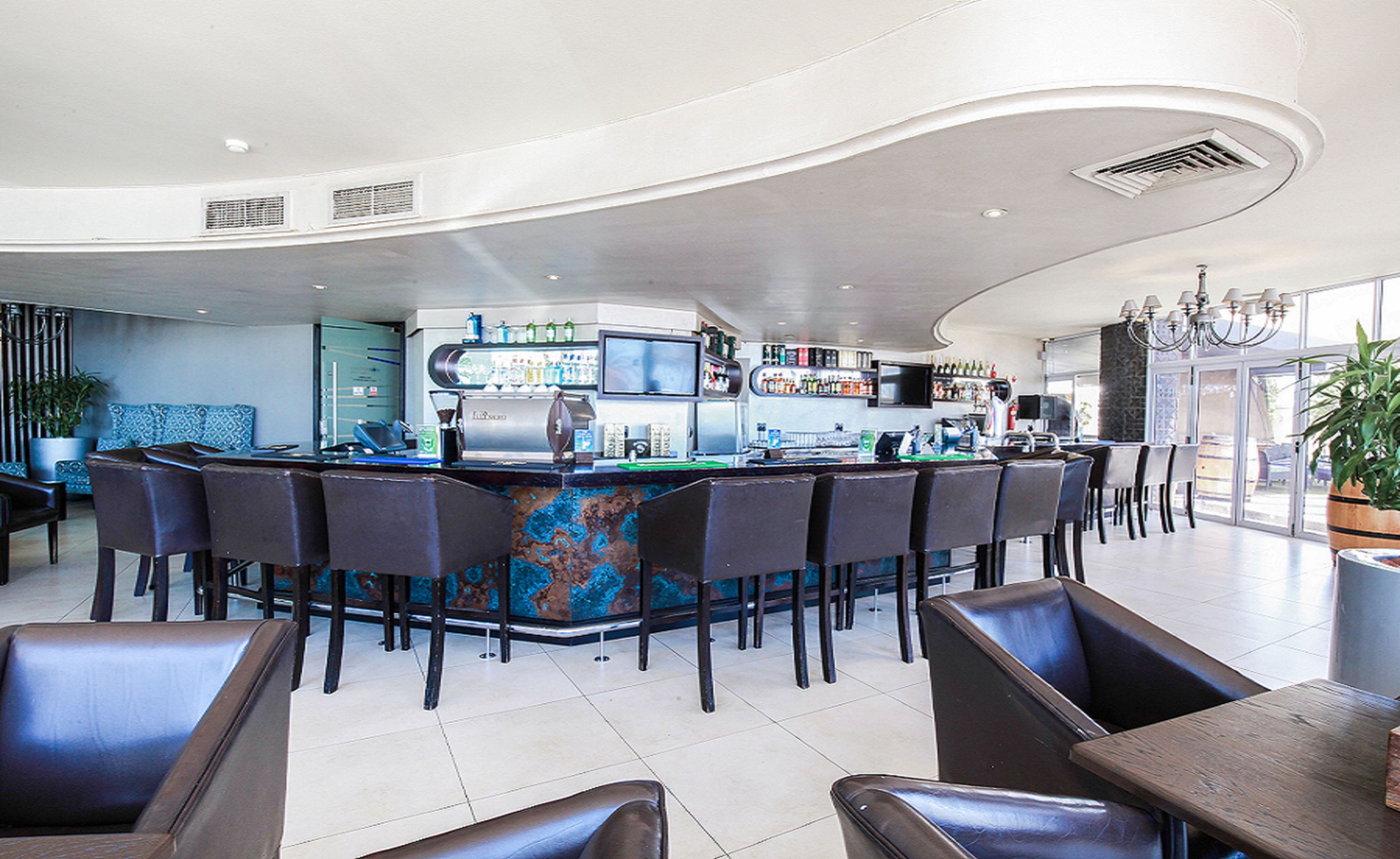 Un área de bar moderna con techo curvo, taburetes y una barra con una pantalla grande.