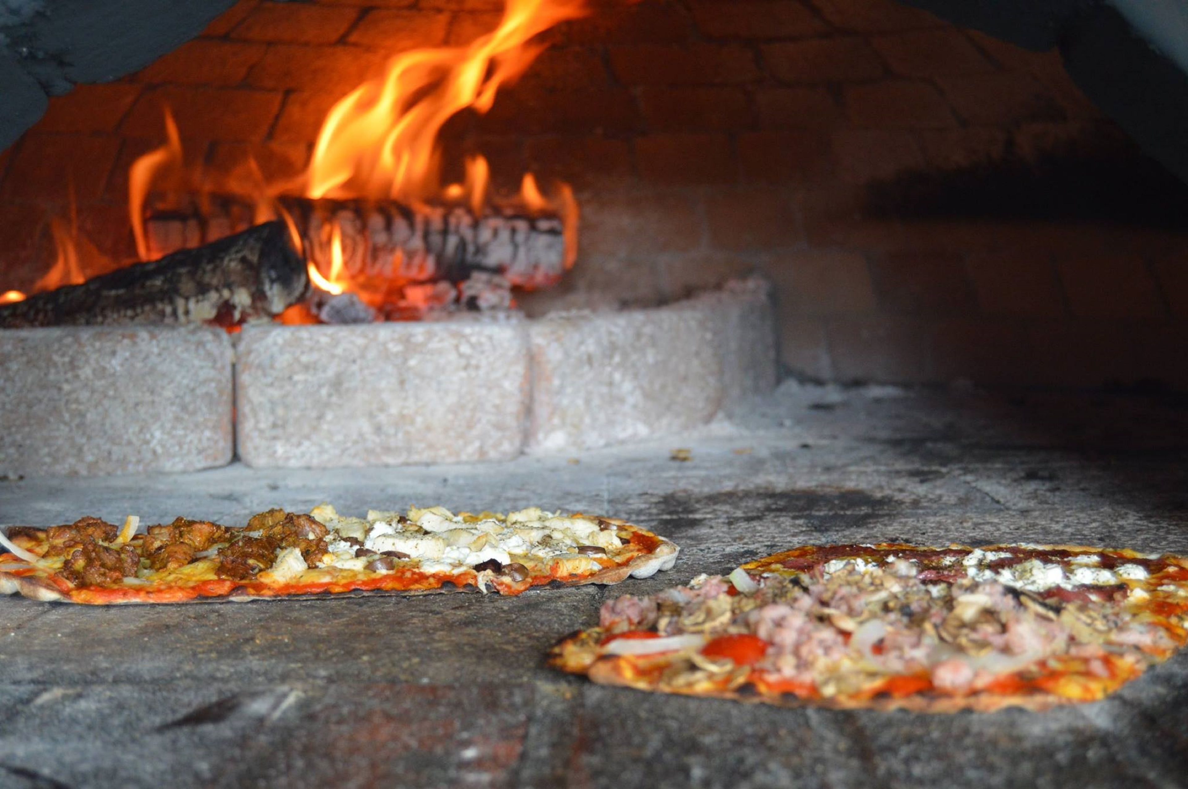 A pizza oven with two pizzas being cooked.