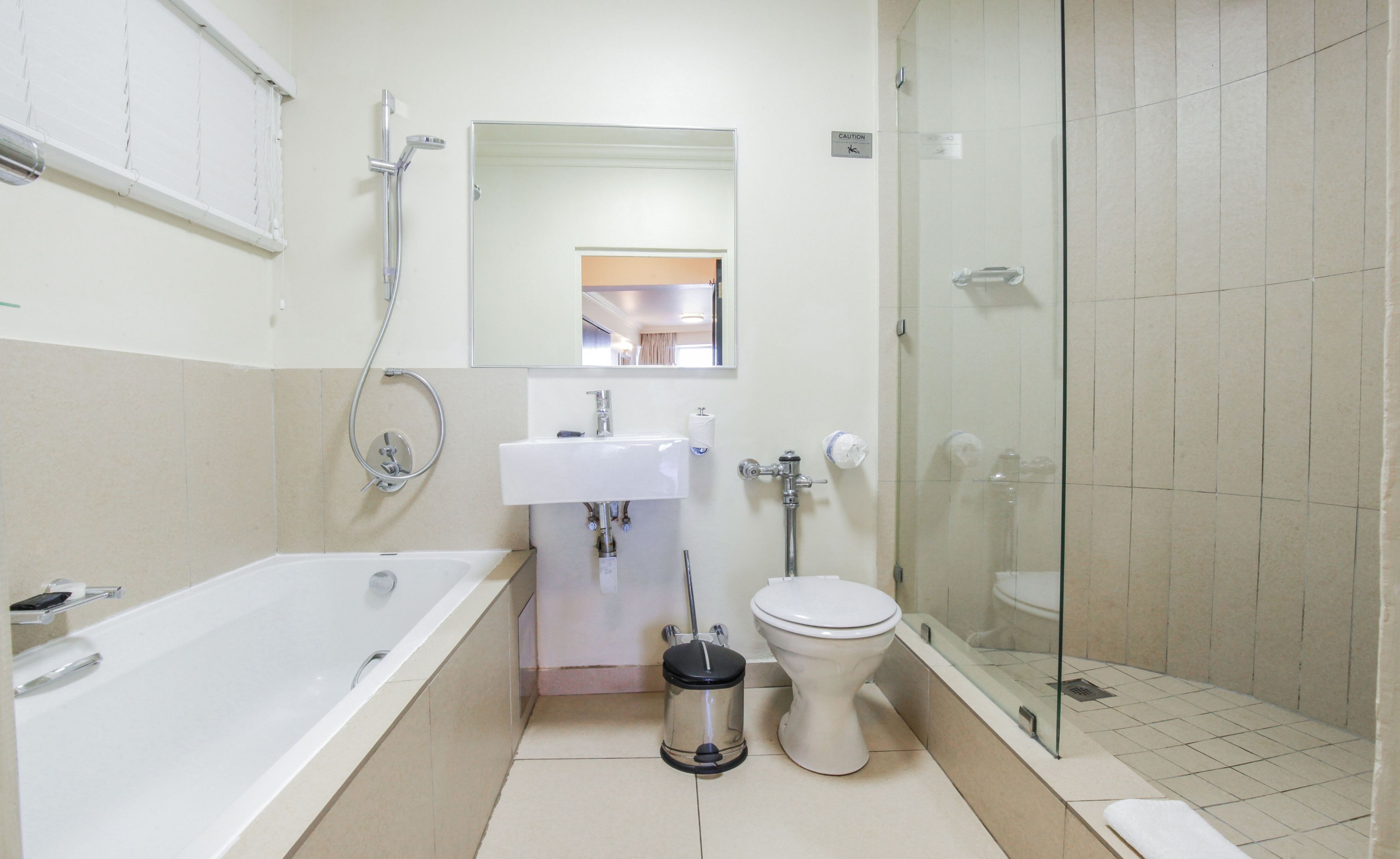 A modern bathroom with a bathtub, sink, toilet, and glass-enclosed shower.