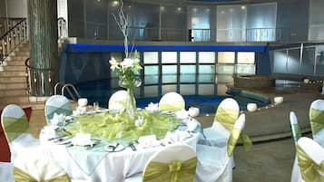 Montaje formal para comedor con mesas redondas, manteles blancos y sillas con cintas verdes.