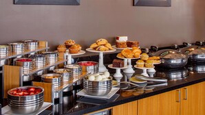 En buffé med ett varierat utbud av mat, inklusive frukt, bakverk och desserter.