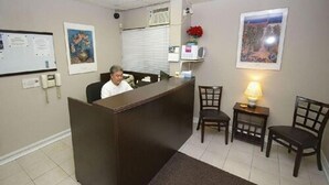 A reception area with a desk, chairs, a whiteboard, and framed pictures on the walls.