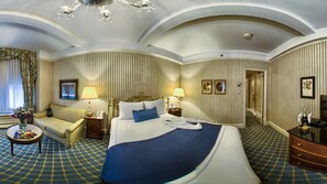 Una habitació d'hotel amb un llit gran, un sofà, un escriptori i una làmpada penjant.