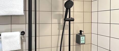 A modern shower with a handheld showerhead and a fixed rain showerhead, mounted on a tiled wall.