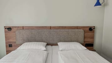 A double bed with a wooden headboard and two pillows.