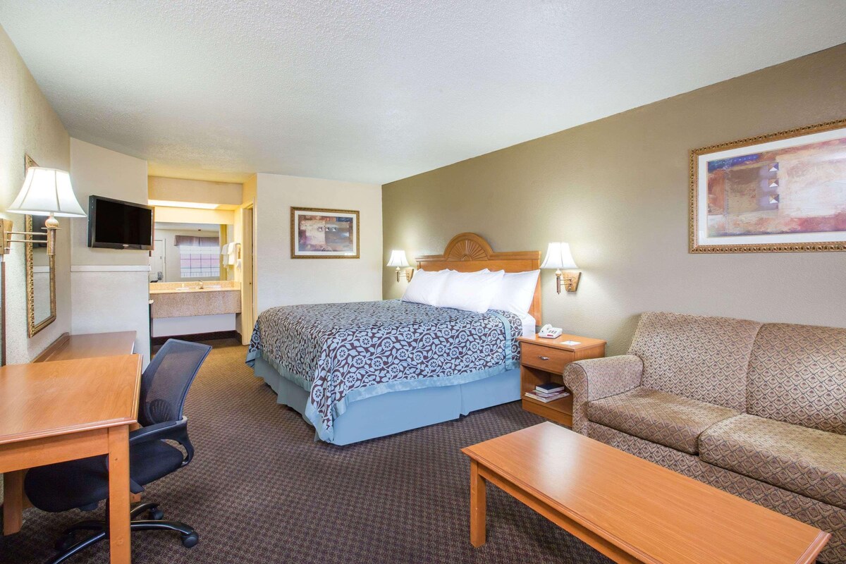 Une chambre d’hôtel comprenant un lit, un bureau, une chaise, un canapé et un téléviseur.