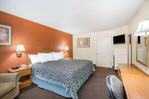 A hotel room with a bed, a desk, a chair, a television, and a door. - Days Inn by Wyndham Tallulah (Tallulah)