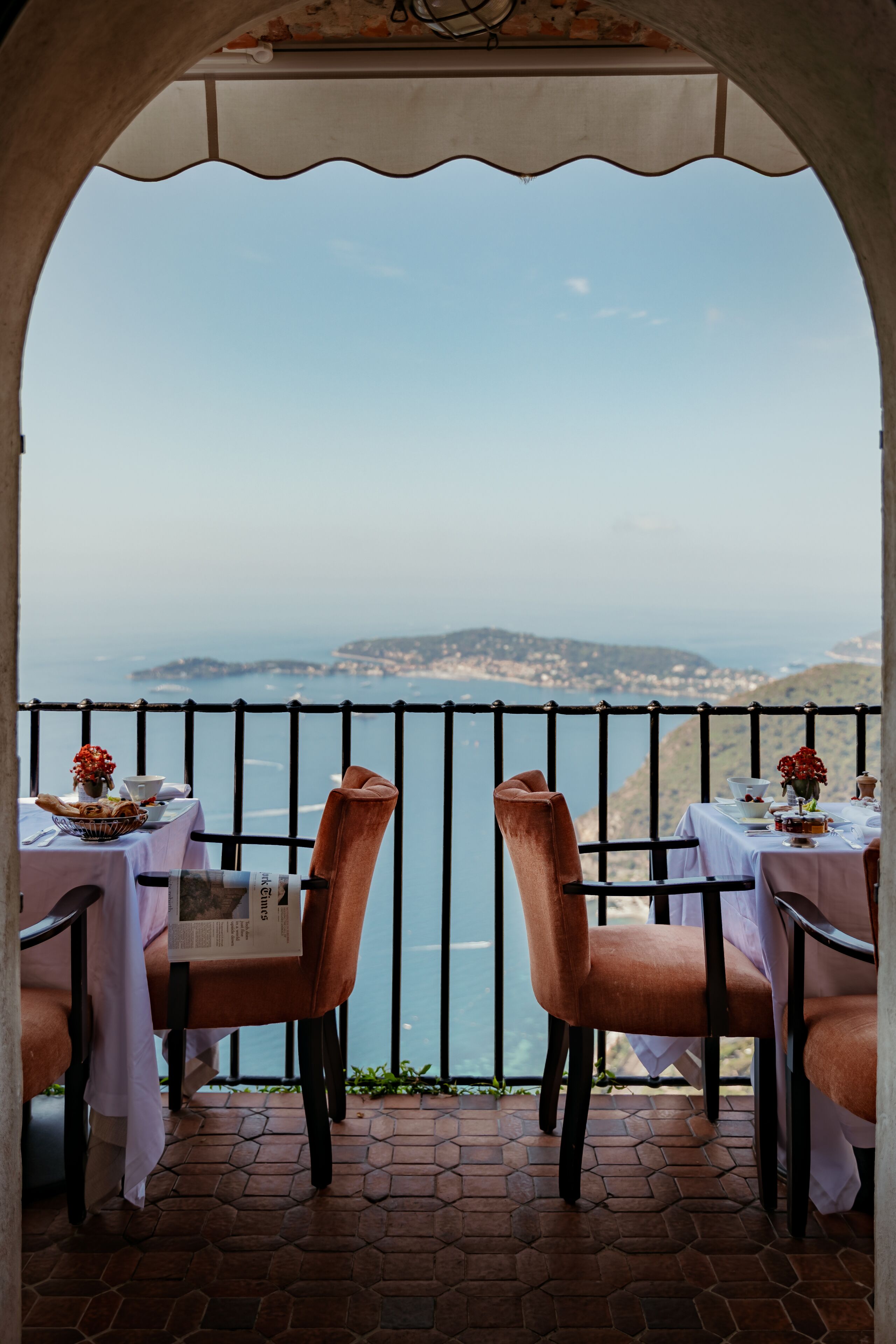 Eine Terrasse mit zwei Tischen und Stühlen mit Blick auf eine malerische Küstenlandschaft.