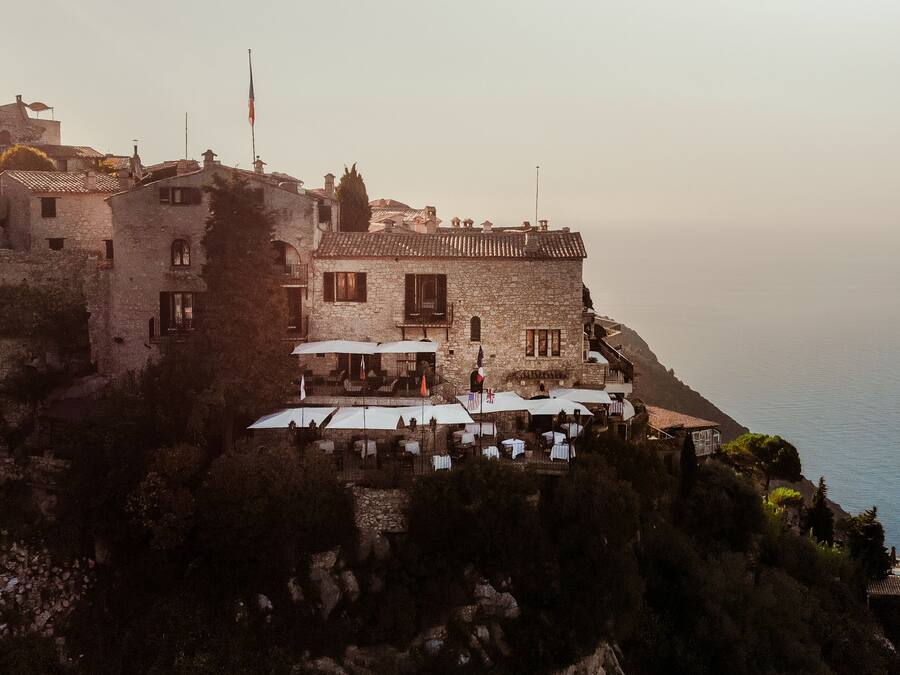 A stone building with outdoor seating and a view of the sea.