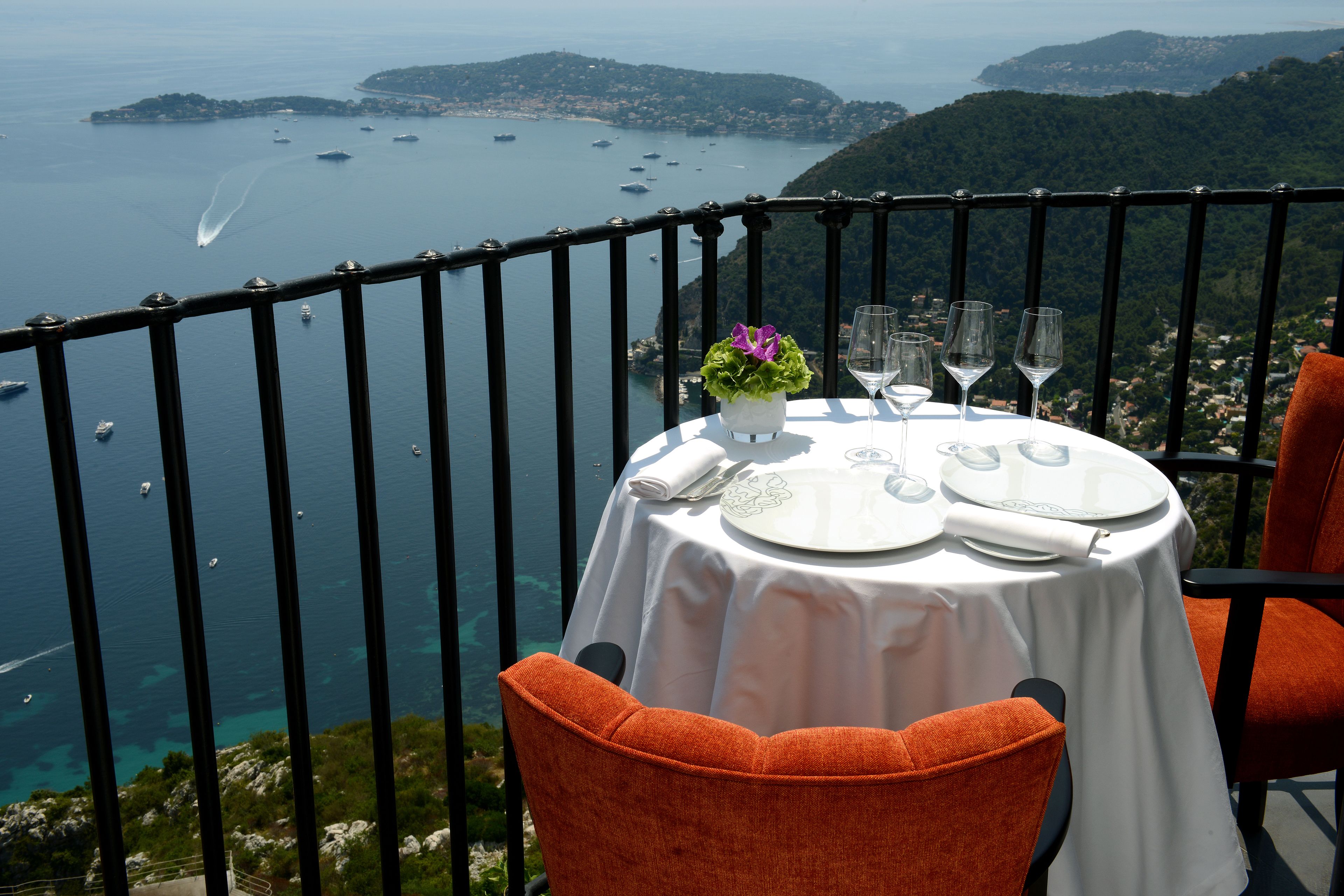 A table set for dining with a view of the sea and hills.