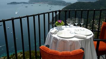 A table set for dining with a view of the sea and hills.