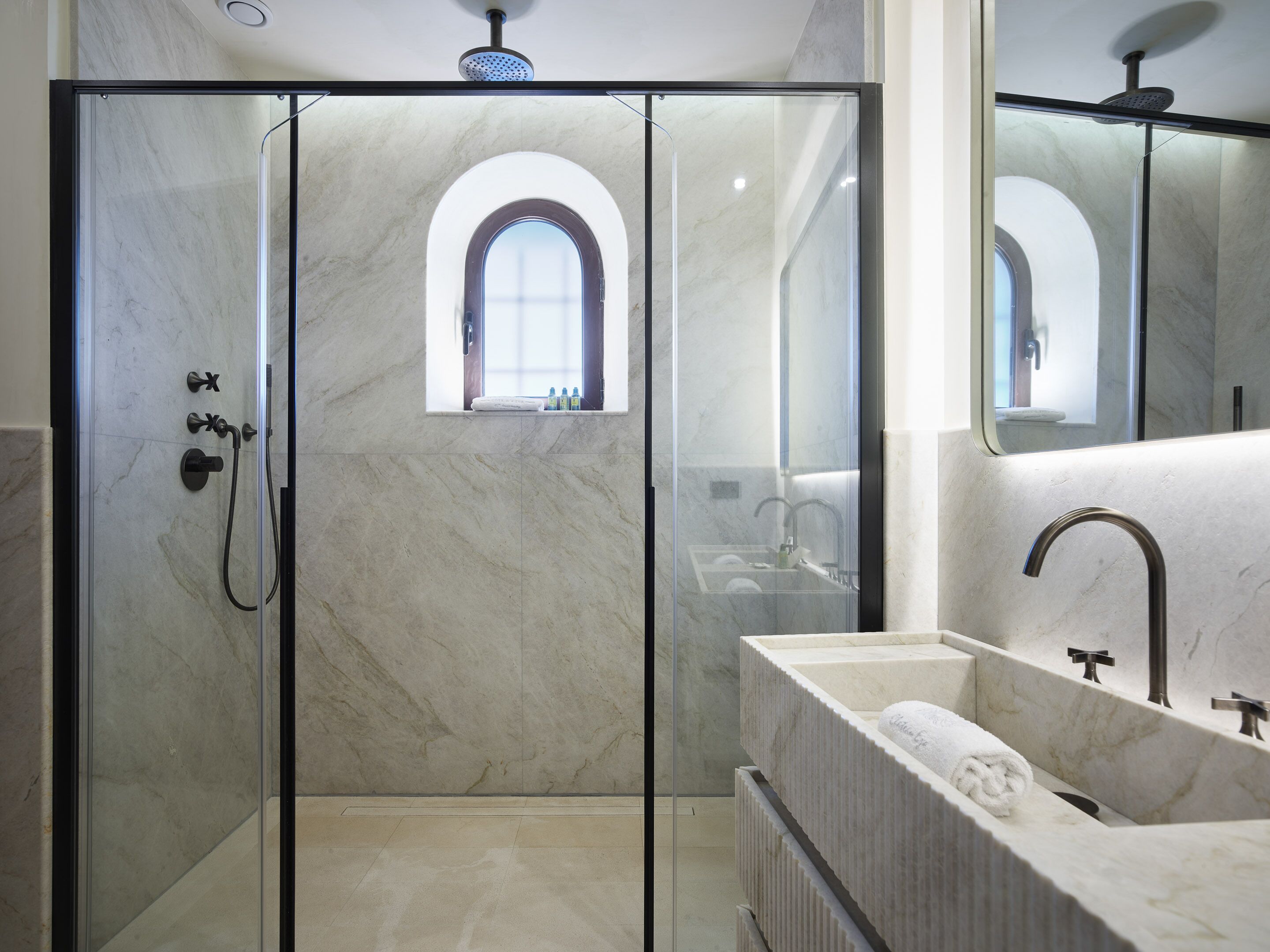 Een moderne badkamer met een douchecabine van glas, een wastafelmeubel en een grote spiegel.