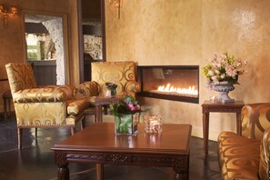 A luxurious living room with a fireplace, ornate chairs, and a coffee table.