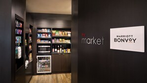 A modern, well-lit hotel market area with shelves stocked with snacks, beverages, and toiletries.