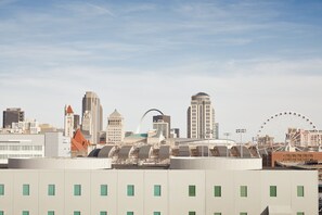 Un paysage urbain avec des bâtiments modernes, une grande roue et une structure arquée remarquable.