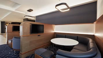 Um interior moderno com mesa redonda e assentos acolchoados, detalhes em madeira e iluminação embutida.