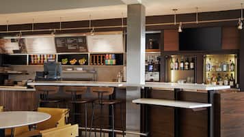 A modern bar area with a menu board, seating, and a bar counter with bottles.