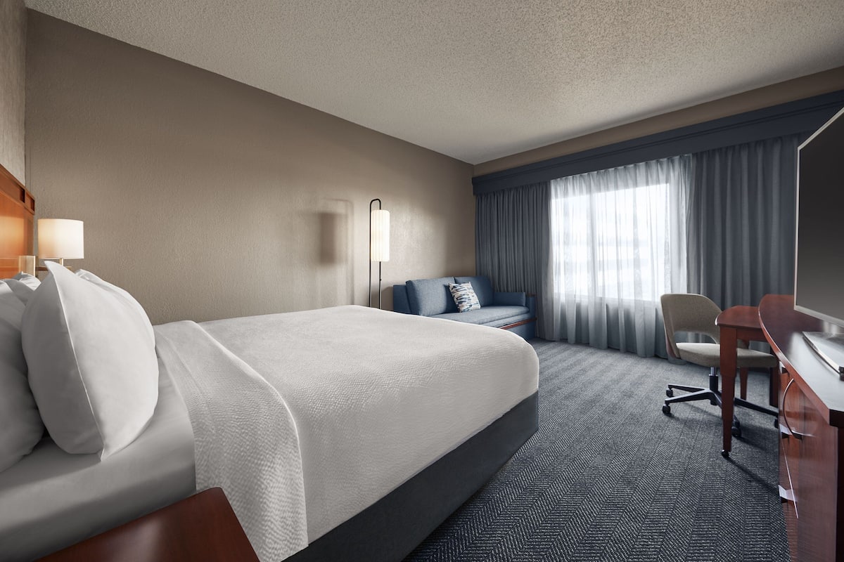 Une chambre d’hôtel avec un grand lit, un bureau, une chaise et un canapé.