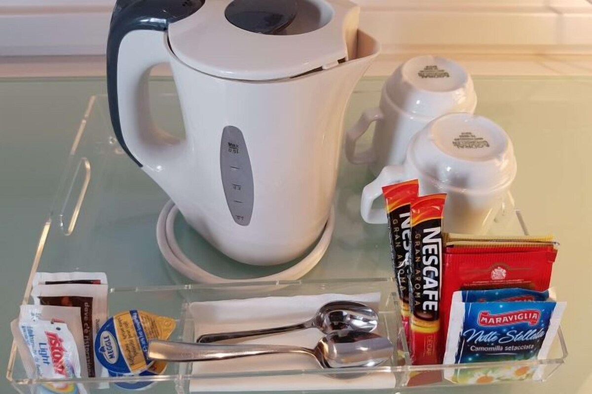 Un coin cuisine équipé d’une machine à café, de salière et de poivrière, d’une cuillère, d’un sachet de sucre et d’un sachet de crème liquide.