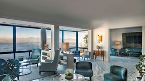 A spacious living area with a large window overlooking a body of water, furnished with modern chairs and a round table. - Hotel Paradiso, BW Signature Collection (Naples)