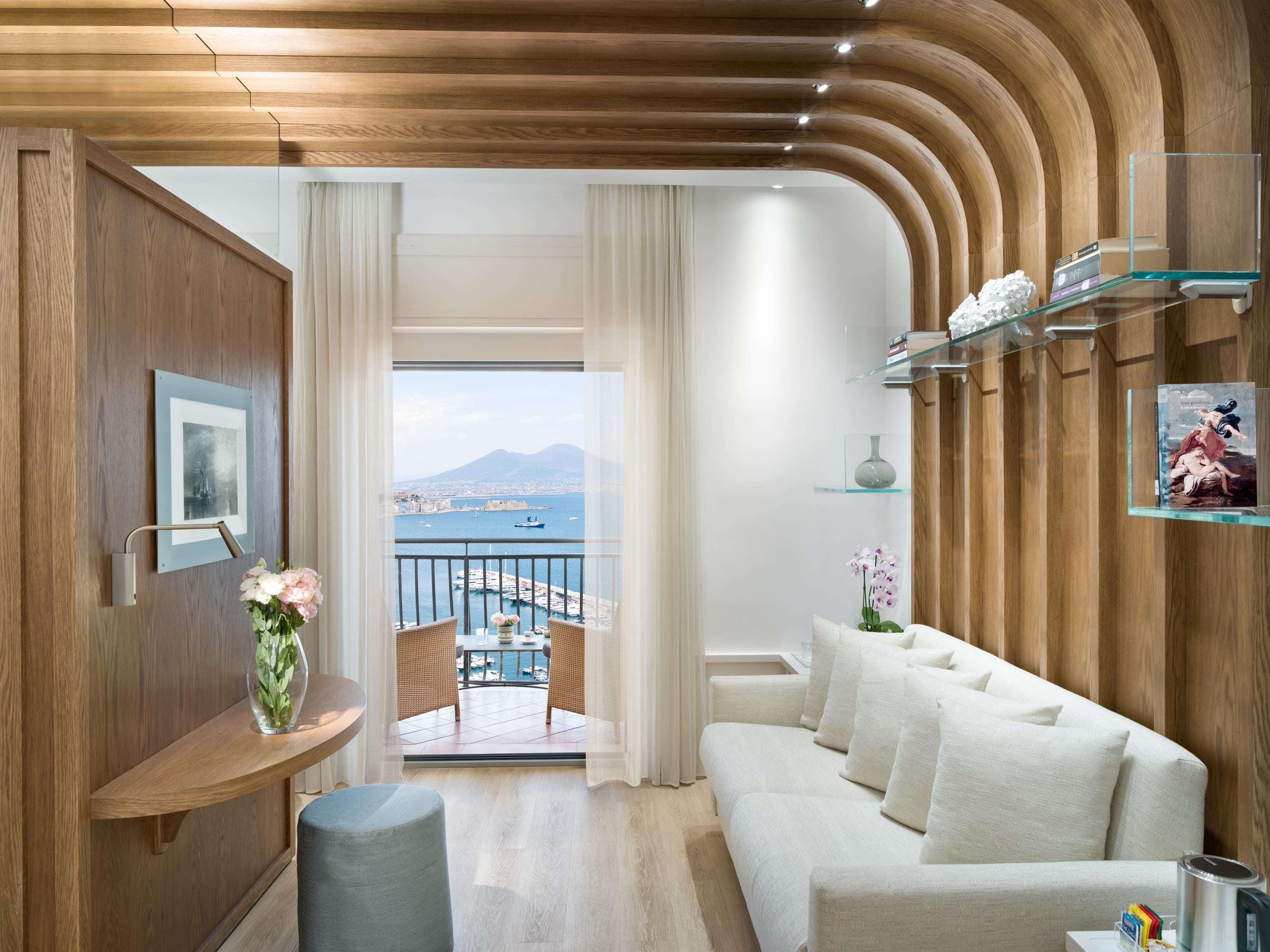 Un salon moderne avec un balcon, un lambris en bois, un canapé, une petite table et une vue sur la mer.