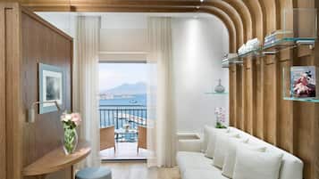 Sala de estar moderna com varanda, painéis de madeira, um sofá, uma mesinha e vista para o mar.