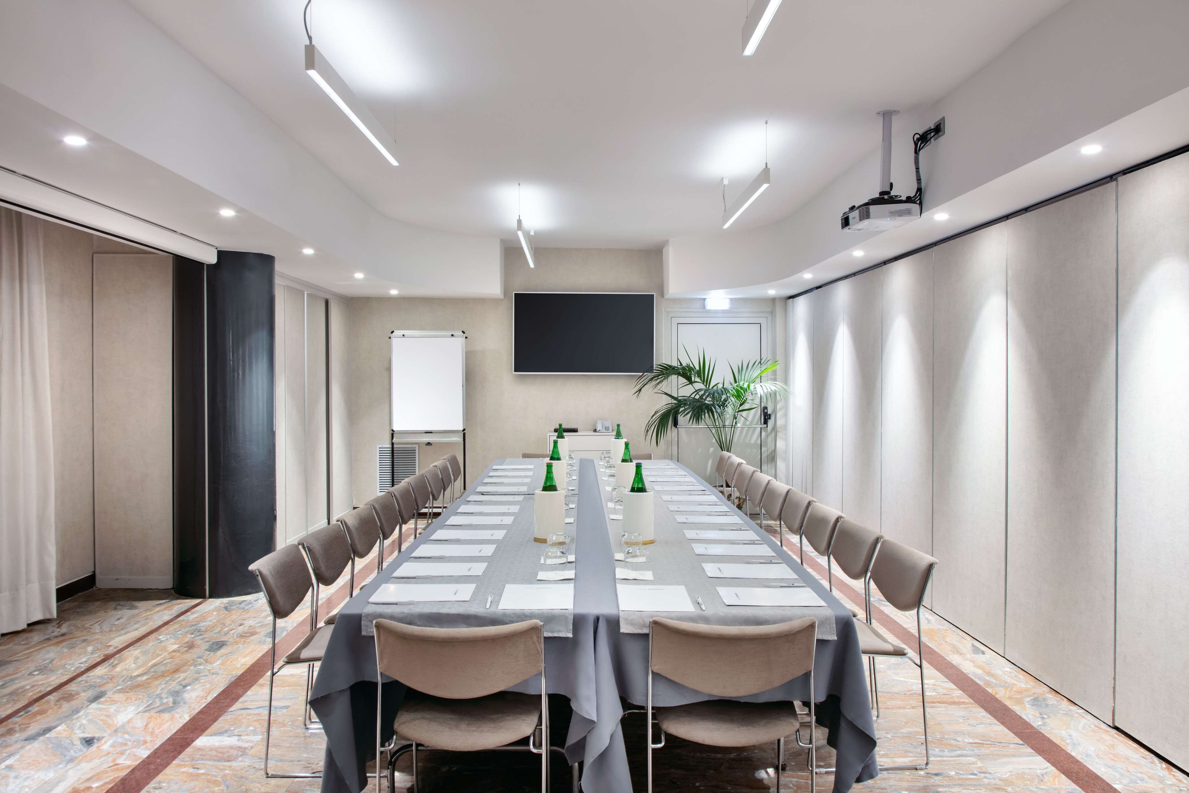 Une salle de conférence équipée d’une longue table, de chaises, d’un projecteur et d’un écran.