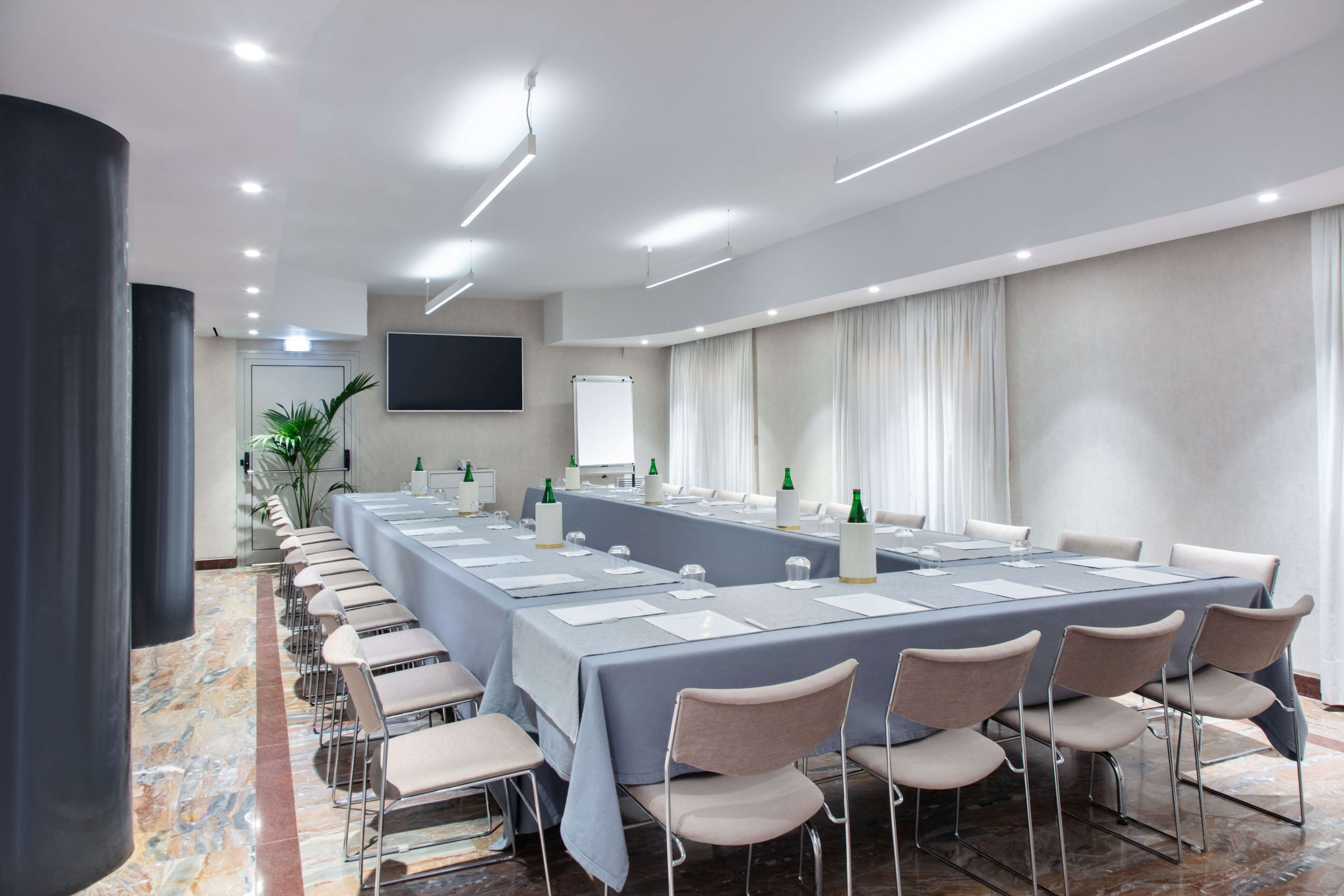 A conference room with a long table, chairs, a screen, and a whiteboard.