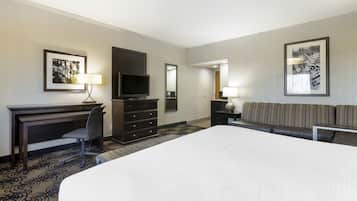 Une chambre d’hôtel avec un grand lit, un bureau avec une chaise, une télévision, une commode et un canapé.