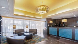 A hotel lobby with a reception desk, seating area, and a patterned rug. - Best Western Plus Midwest Inn (Omaha)