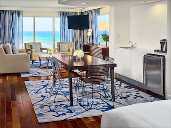 A modern lobby with a central seating area, a reception desk, and a large hanging light fixture. at Sonesta Fort Lauderdale Beach