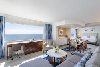A beachfront hotel with a view of the ocean, a palm-lined promenade, and lush greenery. at Sonesta Fort Lauderdale Beach