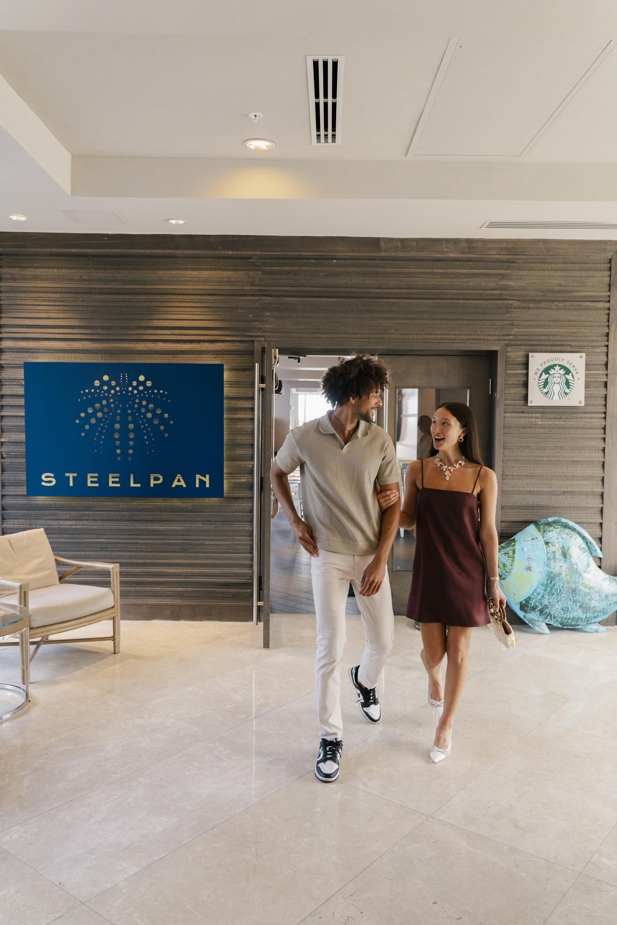 A hotel entrance with a 'STEELPAN' sign, a Starbucks logo, and a modern interior design.
