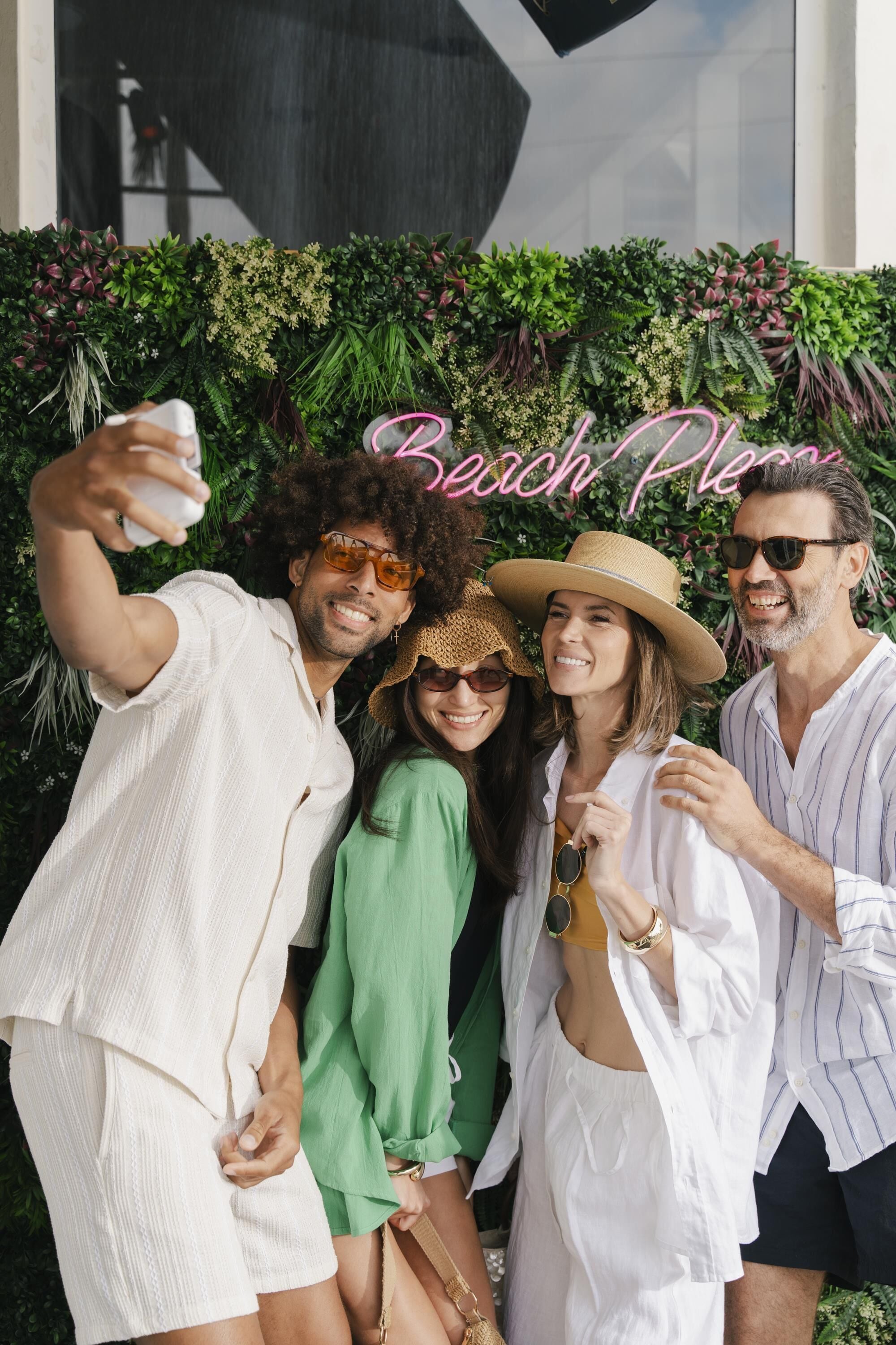 A group of people taking a selfie with a 'Beach Place' sign in the background.