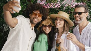 A group of people taking a selfie with a 'Beach Place' sign in the background.