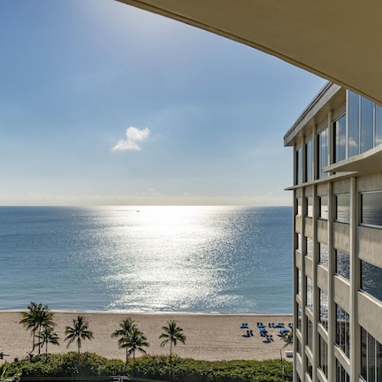 A beachfront hotel with a view of the ocean and palm trees.