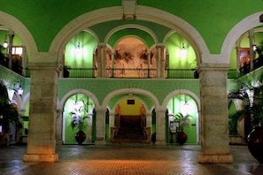 A grand hall with a central staircase, flanked by columns and arches, leading to an upper level. - Holiday Inn Merida by IHG (Mérida)