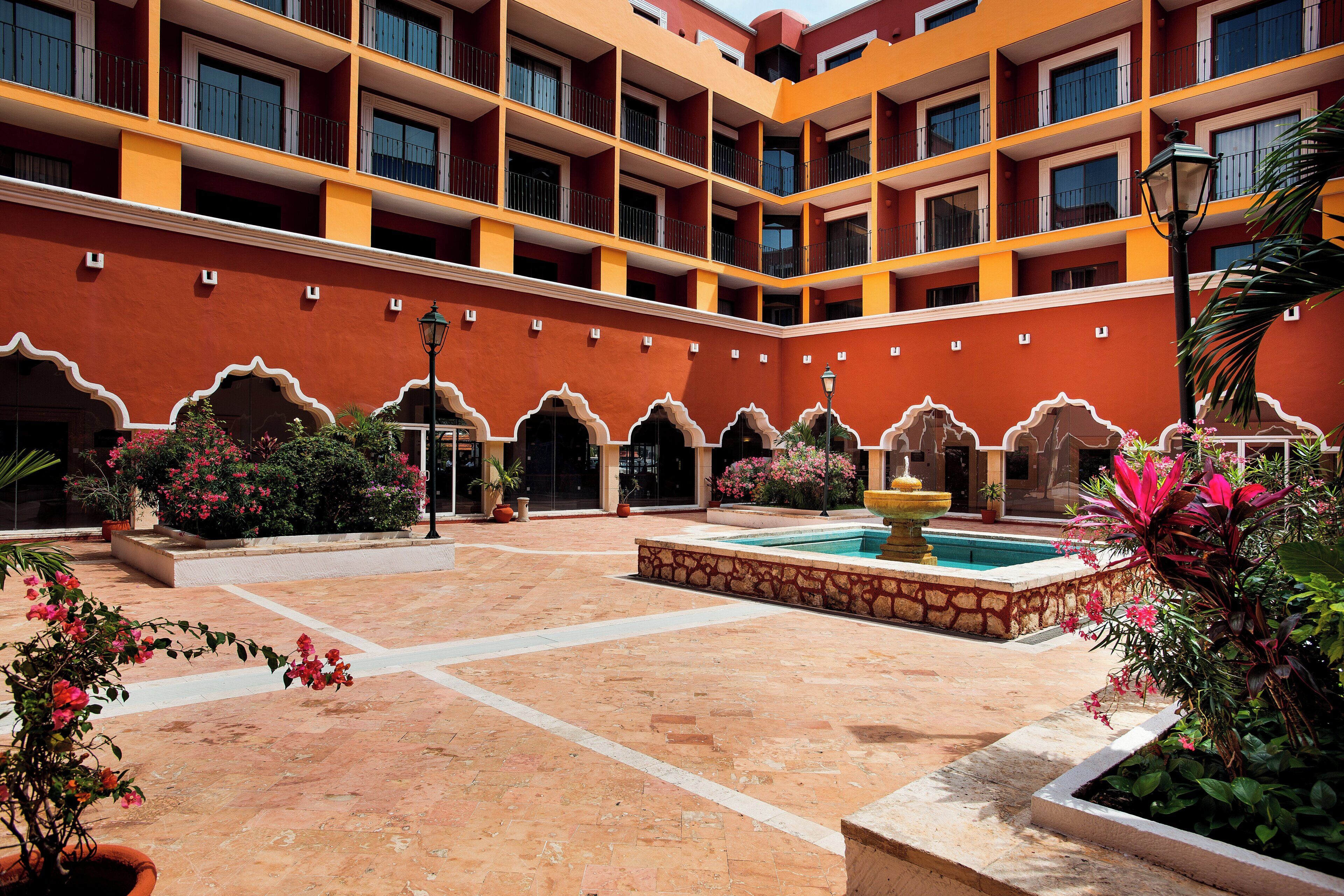 A courtyard with a swimming pool, potted plants, and a building with balconies.